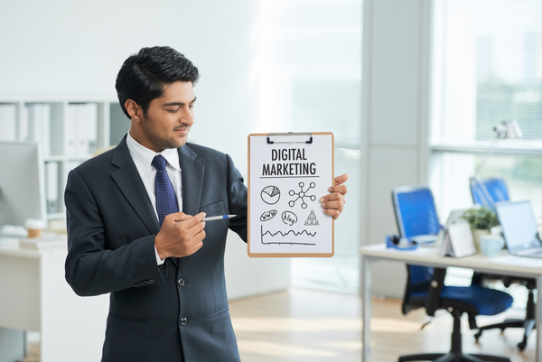 Man in suit standing in office with clipboard and pointing to poster with words